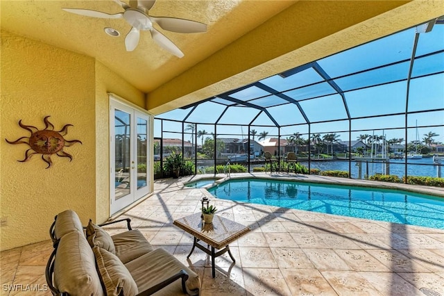 view of pool featuring glass enclosure, ceiling fan, french doors, a water view, and a patio