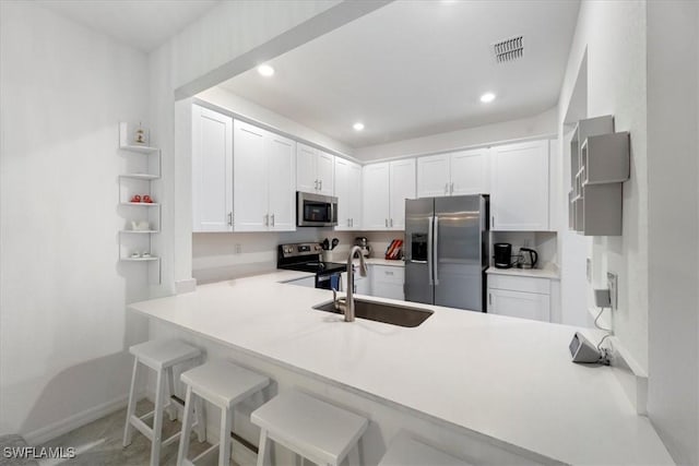 kitchen featuring sink, white cabinetry, a kitchen bar, kitchen peninsula, and appliances with stainless steel finishes