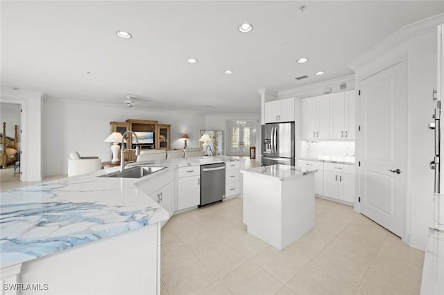 kitchen featuring white cabinets, a large island, appliances with stainless steel finishes, ornamental molding, and a sink