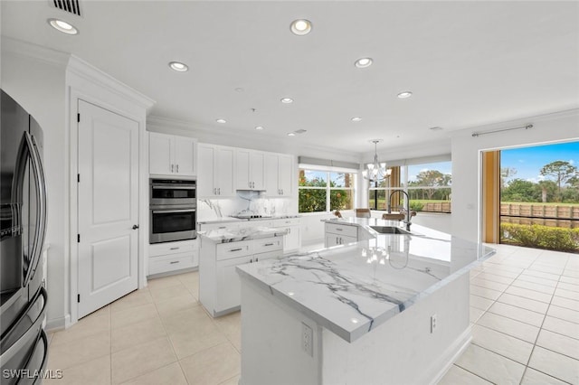 kitchen featuring light stone counters, white cabinetry, an island with sink, pendant lighting, and stainless steel appliances