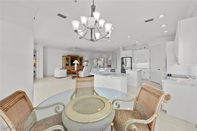 dining room featuring crown molding, sink, light tile patterned floors, and an inviting chandelier