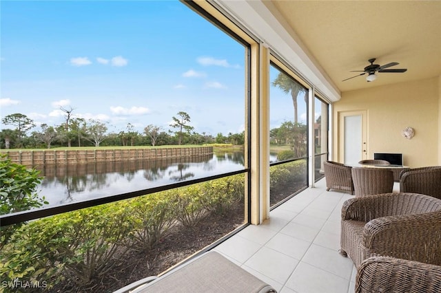 sunroom with ceiling fan and a water view