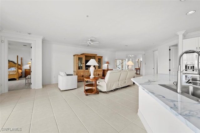 tiled living room featuring crown molding, ceiling fan, and sink