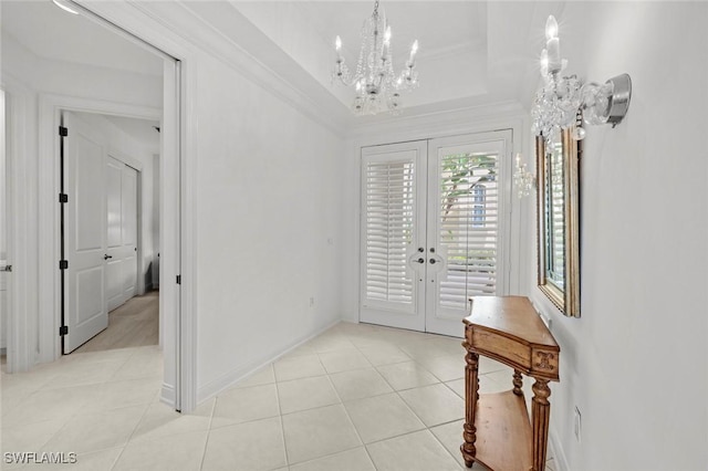 foyer with ornamental molding, light tile patterned floors, a notable chandelier, a raised ceiling, and french doors