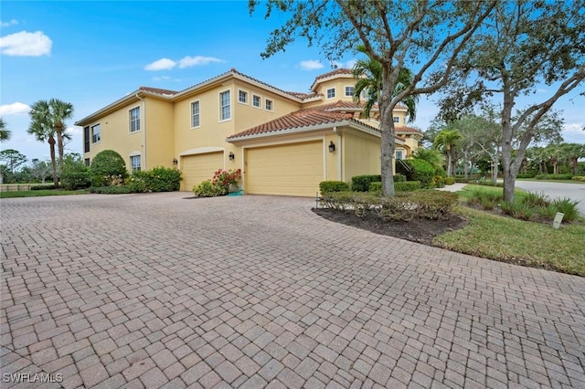 view of front of home with a tiled roof, decorative driveway, and stucco siding