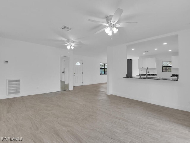 unfurnished living room featuring ceiling fan and sink