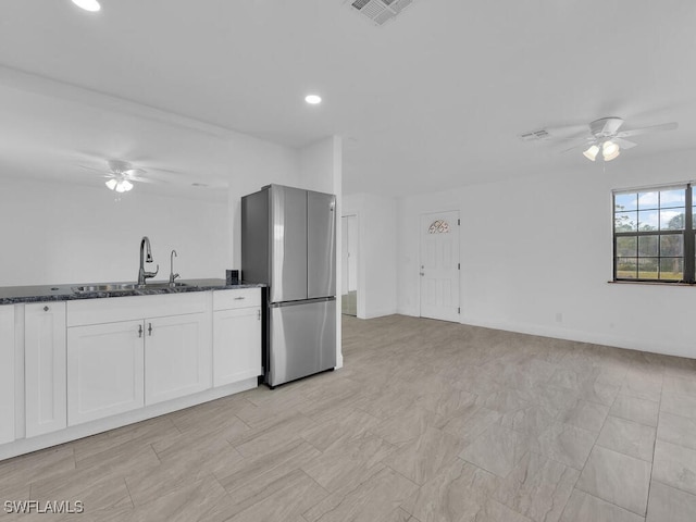 kitchen featuring white cabinets, sink, ceiling fan, dark stone countertops, and stainless steel refrigerator