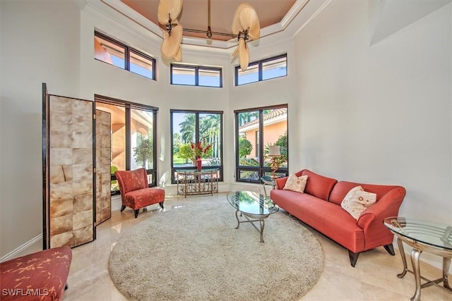 living room with a towering ceiling, ornamental molding, and ceiling fan