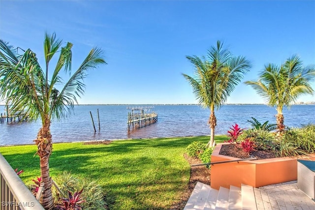 view of dock with a yard and a water view