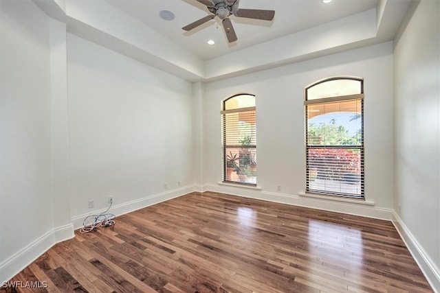 spare room with ceiling fan, a raised ceiling, and wood-type flooring