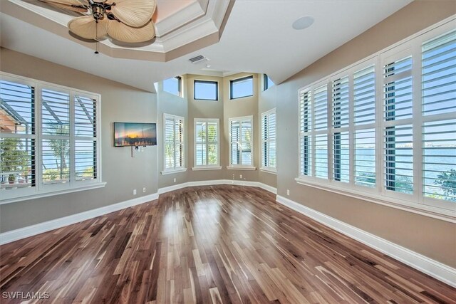 empty room featuring ceiling fan, ornamental molding, hardwood / wood-style flooring, and a tray ceiling