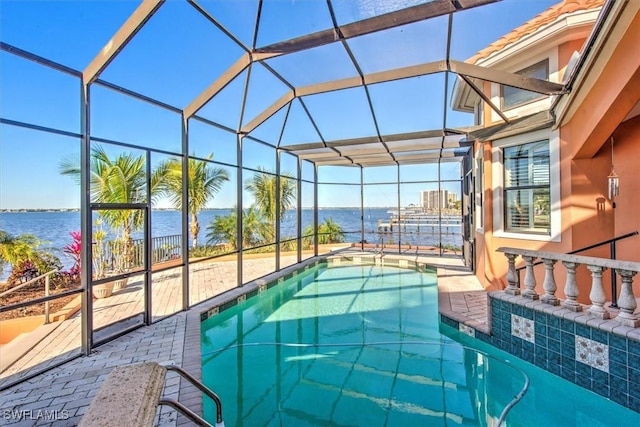 view of pool with a patio, glass enclosure, and a water view