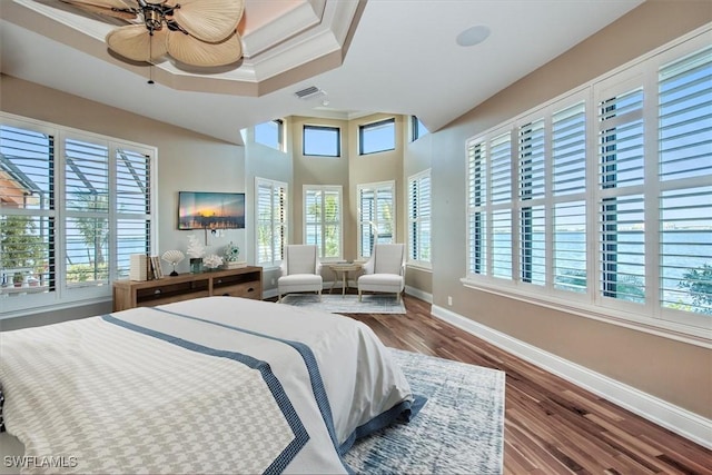 bedroom with hardwood / wood-style floors, a raised ceiling, ceiling fan, and crown molding