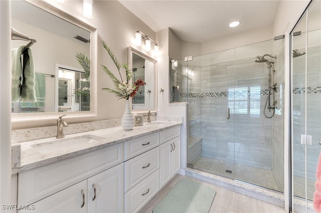 bathroom with a shower with shower door, tile patterned floors, and vanity