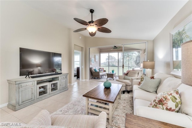 living room featuring ceiling fan, light tile patterned floors, and vaulted ceiling