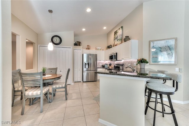 kitchen with white cabinetry, stainless steel appliances, dark stone countertops, decorative backsplash, and light tile patterned floors