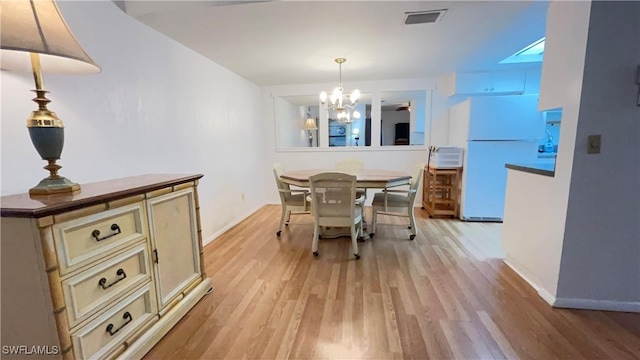 dining area with light hardwood / wood-style flooring and a notable chandelier