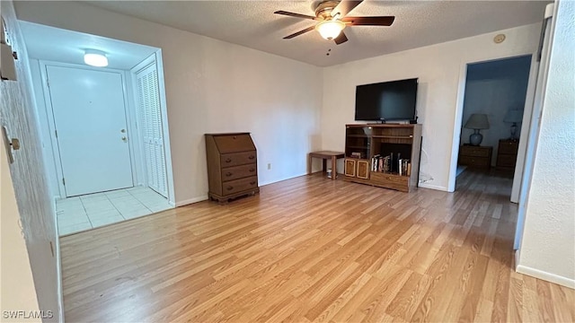 unfurnished living room featuring a textured ceiling, light hardwood / wood-style flooring, and ceiling fan