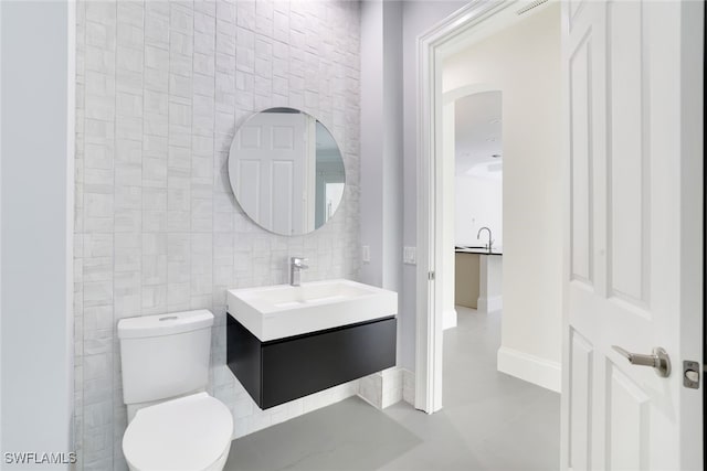 bathroom with tile walls, vanity, and toilet