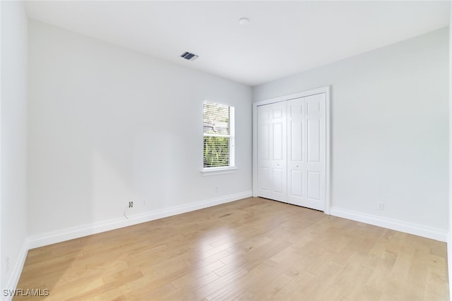 unfurnished bedroom with light wood-type flooring and a closet