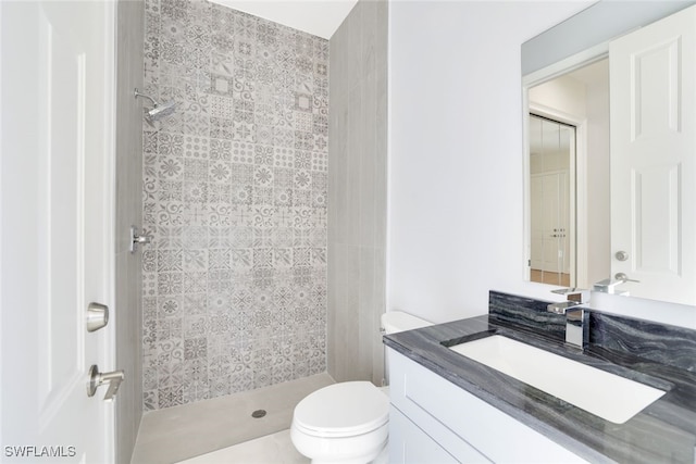 bathroom featuring vanity, toilet, and a tile shower