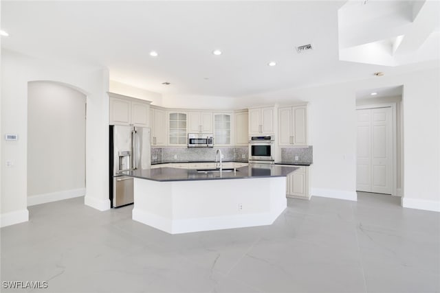 kitchen featuring stainless steel appliances, sink, a center island with sink, and backsplash