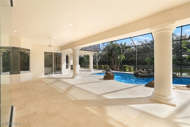 view of swimming pool featuring ceiling fan, a water view, glass enclosure, and a patio area