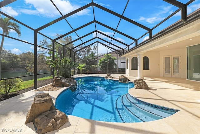 view of swimming pool with a patio, a water view, glass enclosure, and french doors