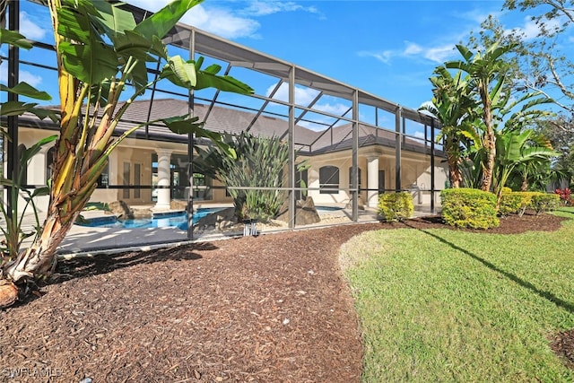 back of property with a yard, a patio area, and glass enclosure