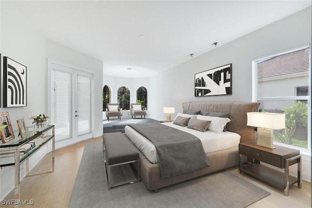 bedroom featuring multiple windows, access to exterior, and light hardwood / wood-style flooring