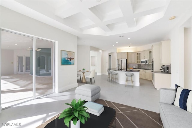 tiled living room with ceiling fan, coffered ceiling, and beam ceiling