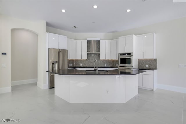 kitchen featuring sink, a kitchen island with sink, white cabinetry, stainless steel appliances, and wall chimney exhaust hood