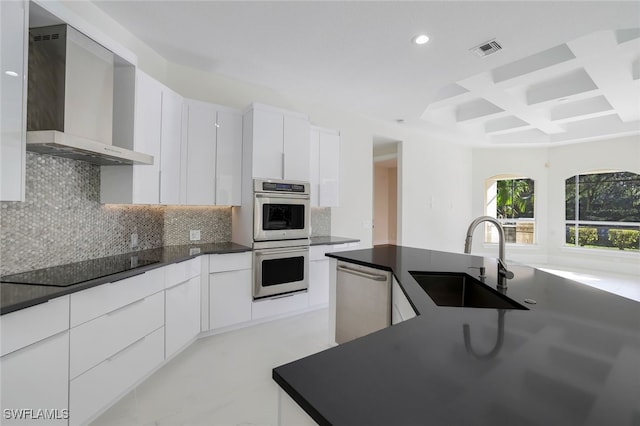 kitchen with white cabinetry, sink, coffered ceiling, stainless steel appliances, and wall chimney exhaust hood