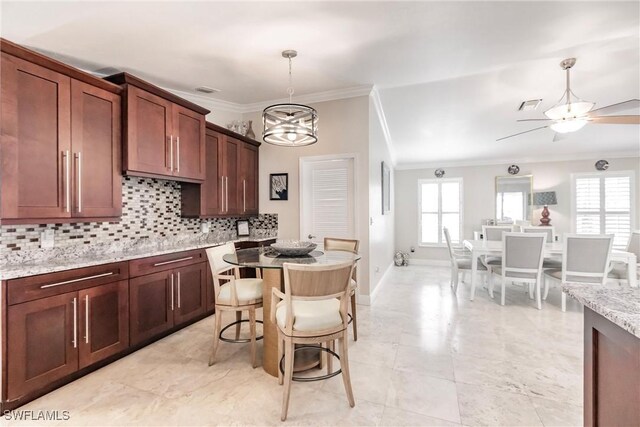 kitchen featuring crown molding, ceiling fan with notable chandelier, light stone counters, decorative backsplash, and decorative light fixtures