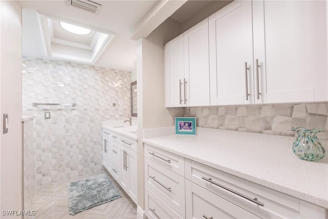 interior space with a raised ceiling, white cabinetry, and visible vents