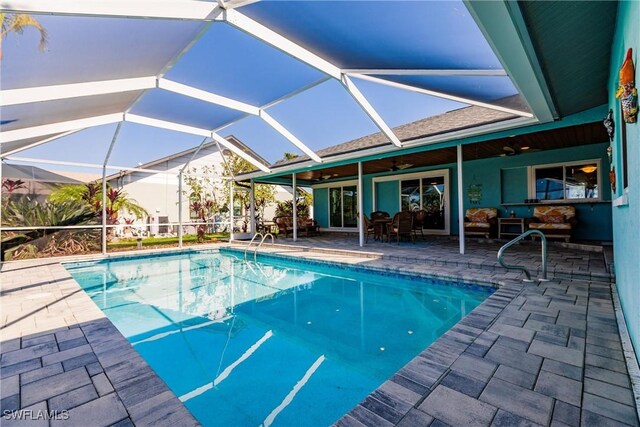 view of swimming pool featuring ceiling fan, a lanai, and a patio