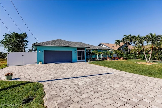 view of front facade with a garage, decorative driveway, a gate, stucco siding, and a front yard