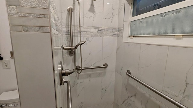 bathroom featuring tiled shower and toilet