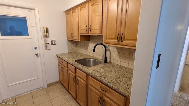 kitchen with decorative backsplash, light stone counters, sink, and light tile patterned flooring