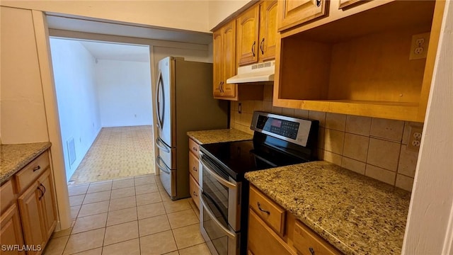 kitchen with light tile patterned floors, light stone countertops, appliances with stainless steel finishes, and tasteful backsplash