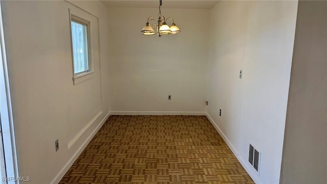 empty room with dark parquet floors and an inviting chandelier