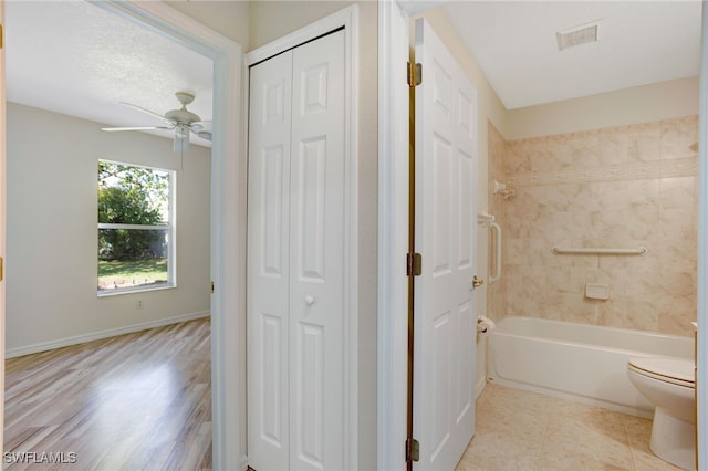 bathroom with ceiling fan, tiled shower / bath combo, and toilet