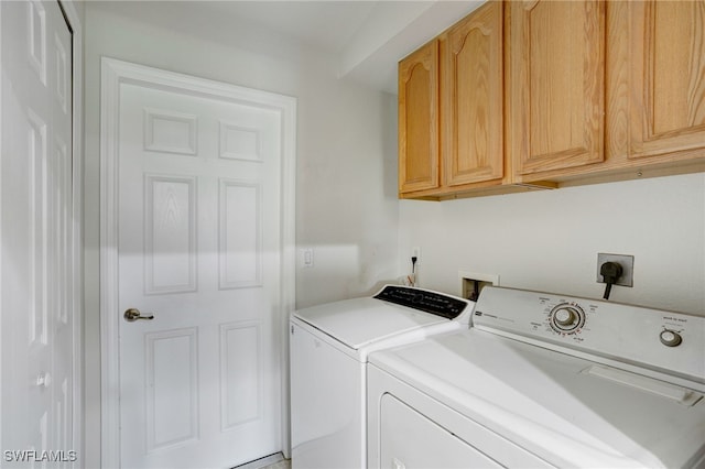 clothes washing area featuring washer and clothes dryer and cabinets