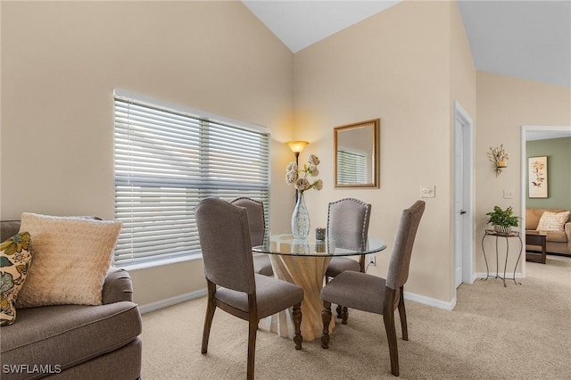 carpeted dining area featuring high vaulted ceiling