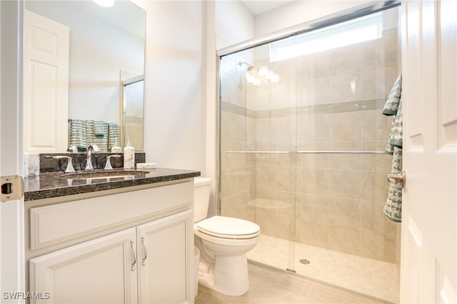 bathroom featuring vanity, a shower with shower door, and toilet