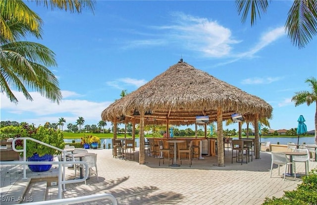 view of home's community featuring a bar, a gazebo, a patio area, and a water view