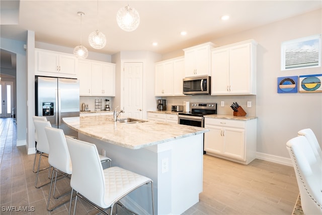 kitchen featuring sink, hanging light fixtures, a center island with sink, appliances with stainless steel finishes, and white cabinets