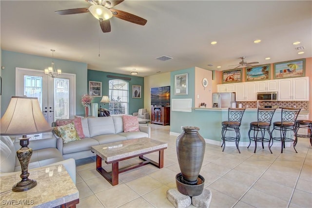 tiled living room with ceiling fan with notable chandelier