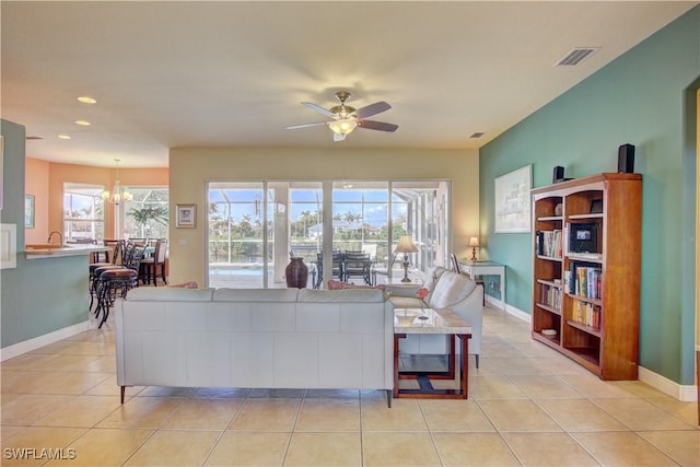 tiled living room featuring ceiling fan with notable chandelier