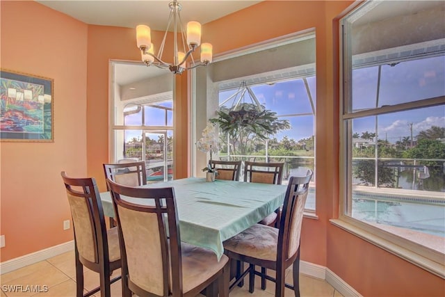 dining area featuring a notable chandelier, a water view, a healthy amount of sunlight, and light tile patterned flooring